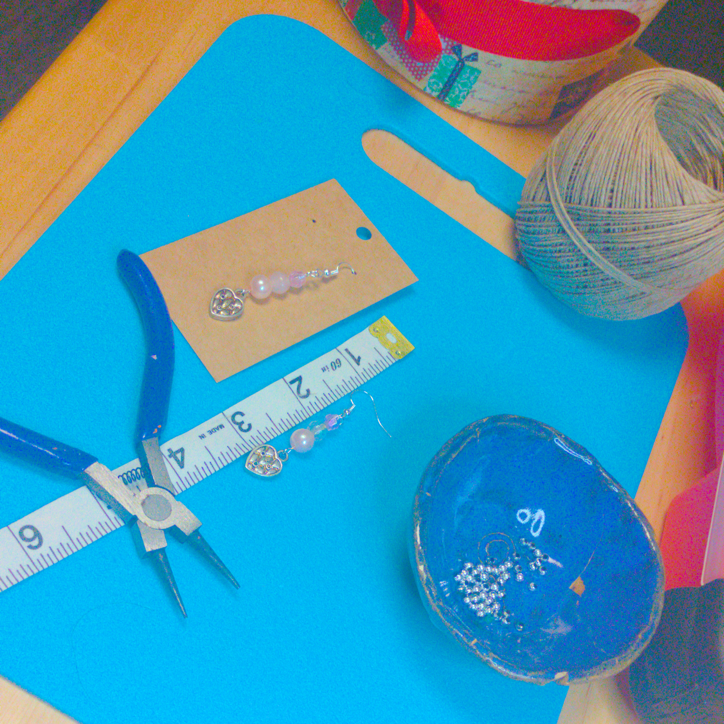An image of a pair of pink handmade earrings being measured on a work table. The pair is 2.25 inches long.