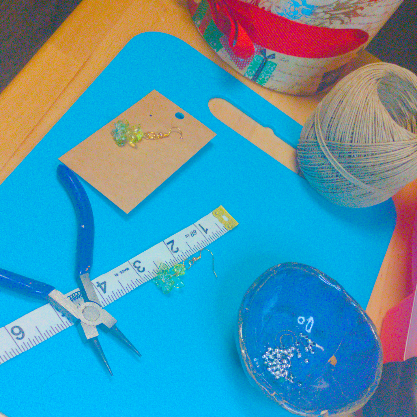 An image of a pair of green handmade earrings being measured on a work table. The pair is 1.75 inches long.
