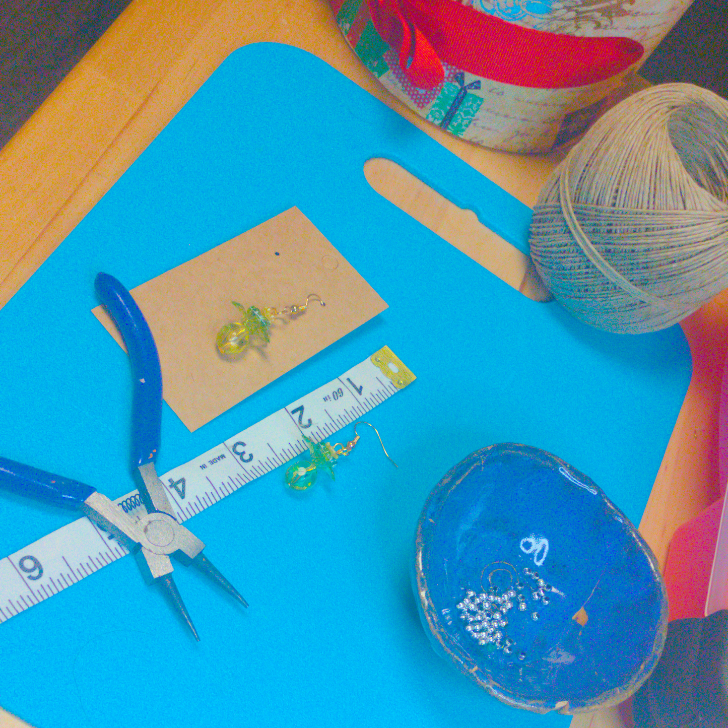 An image of a pair of green handmade earrings being measured on a work table. The pair is 1.75 inches long.