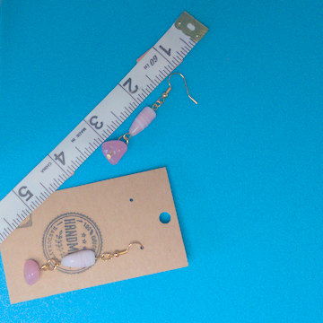 A pair of pink earrings being measured on a work table. The pair is 2 inches long.
