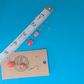 A pair of orange earrings being measured on a work table. The pair is 2.25 inches long.