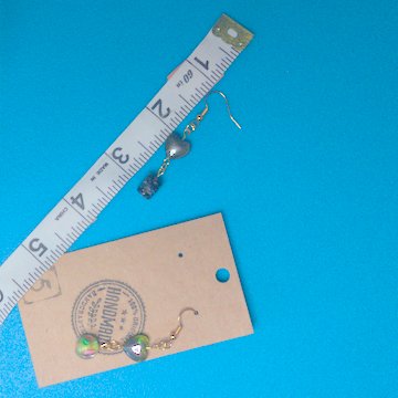 A pair of green earrings being measured on a work table. The pair is 2 inches long.