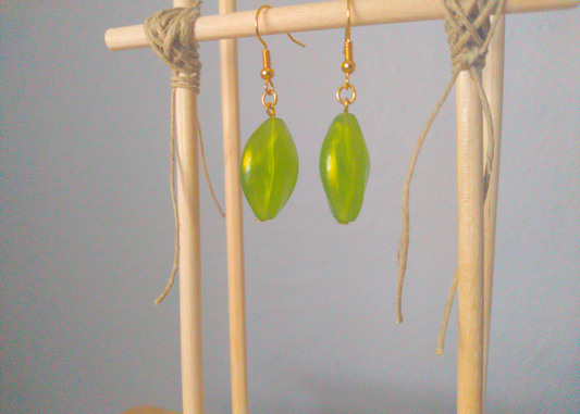 A front facing image of a pair of green handmade earrings being displayed on a stand. There is an oval shaped green bead with a gold shimmer that is the focal piece of the earrings. The hooks are a golden color.