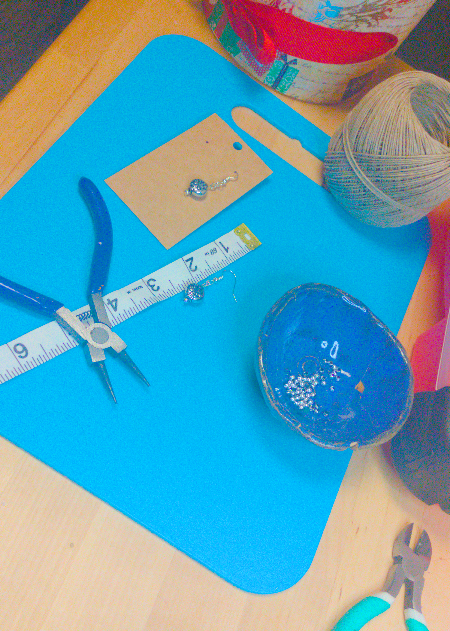 An image of a pair of silver earrings being measured on a work table. The pair is 1.5 inches long.