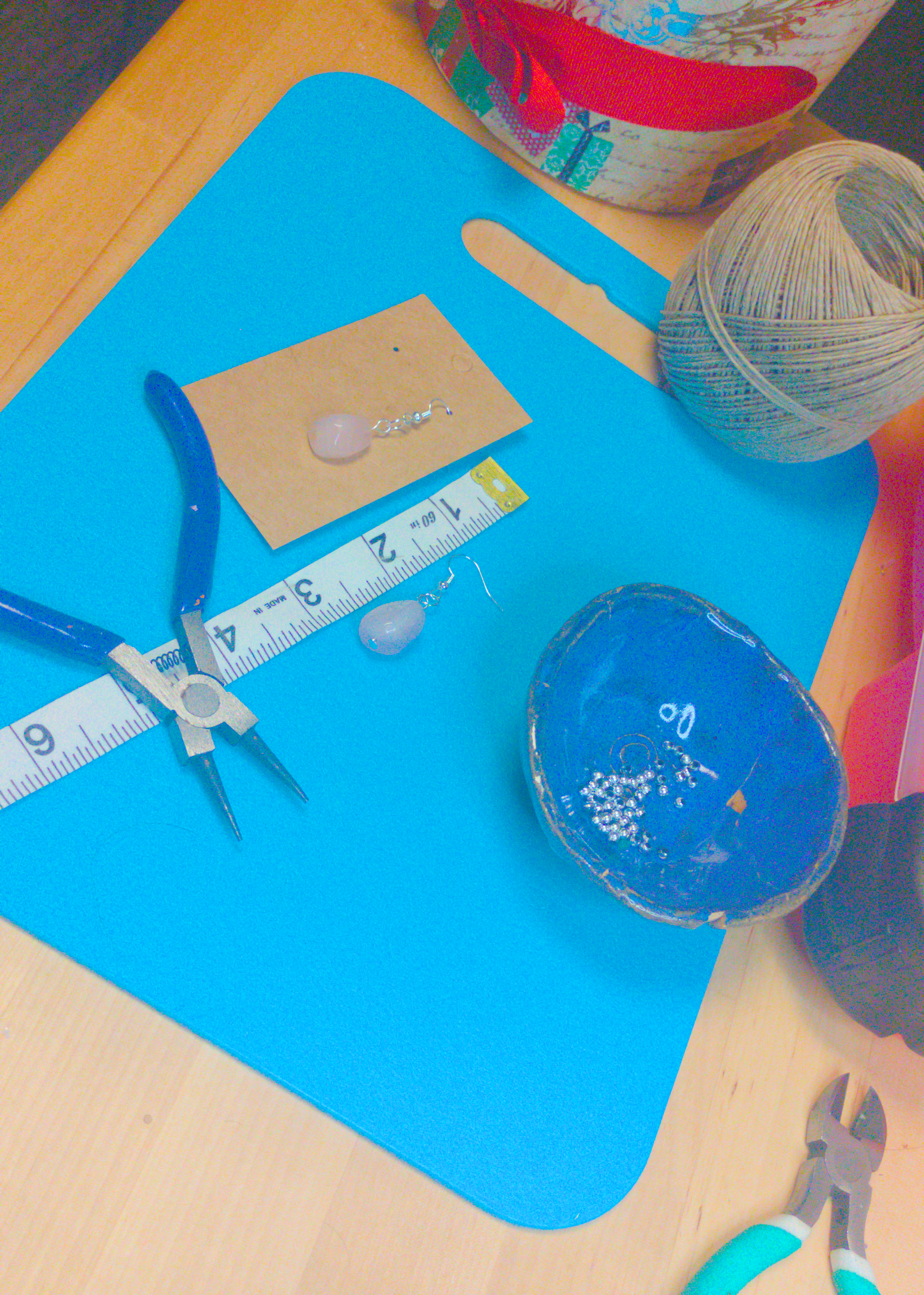 An image of a pair of pink handmade earrings being measured on a work table. The pair is 1.75 inches long.