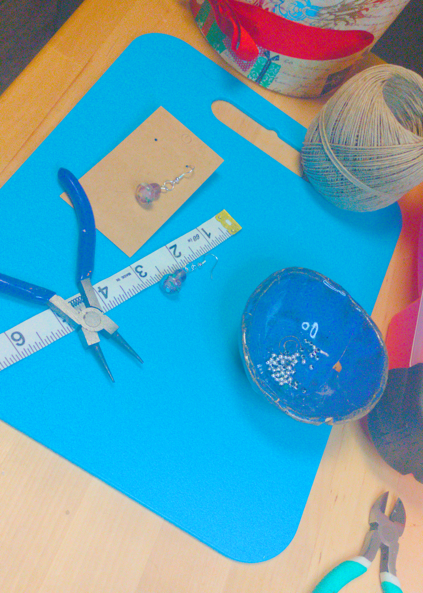 An image of a pair of purple handmade earrings being measured on a work table. The pair is 1.75 inches long.