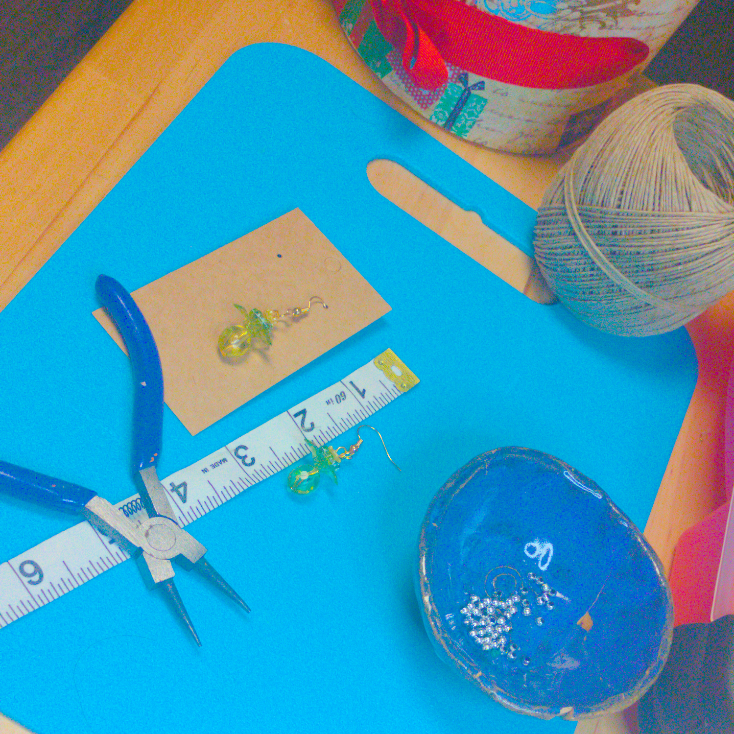 An image of a pair of green handmade earrings being measured on a work table. The pair is 1.75 inches long.