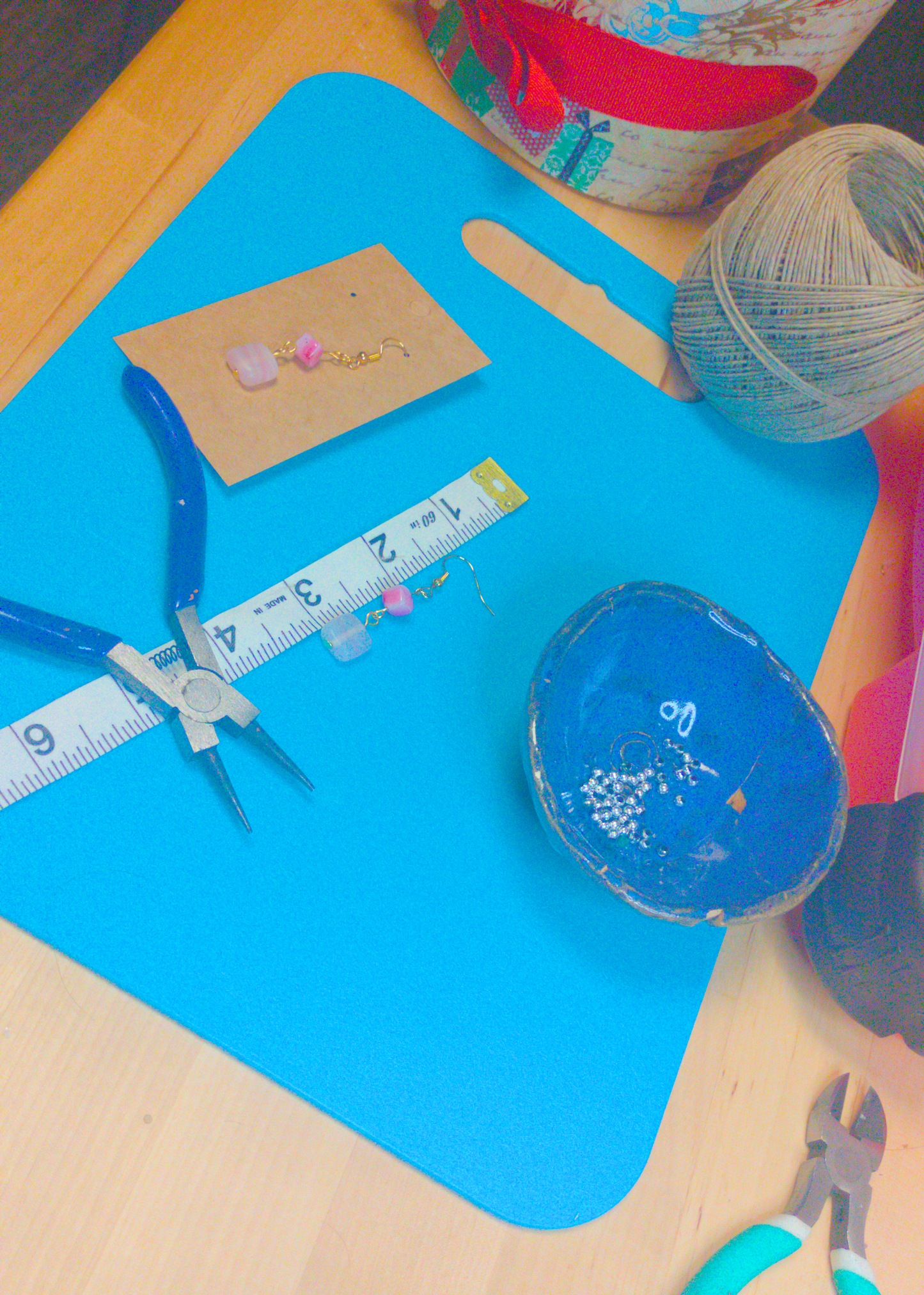 An image of a pair of pink handmade earrings being measured on a work table. The pair is 2 inches long.