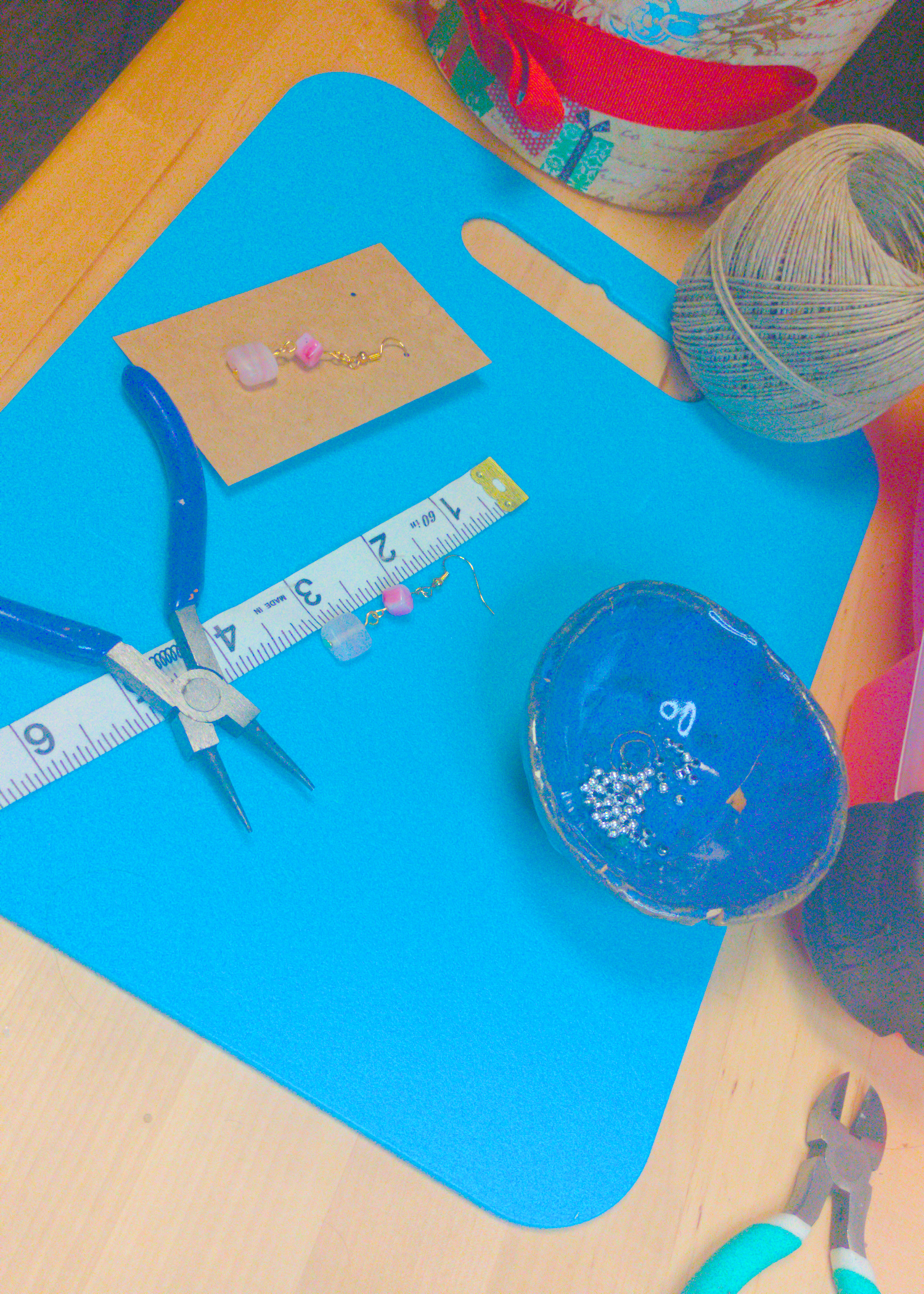 An image of a pair of pink handmade earrings being measured on a work table. The pair is 2 inches long.