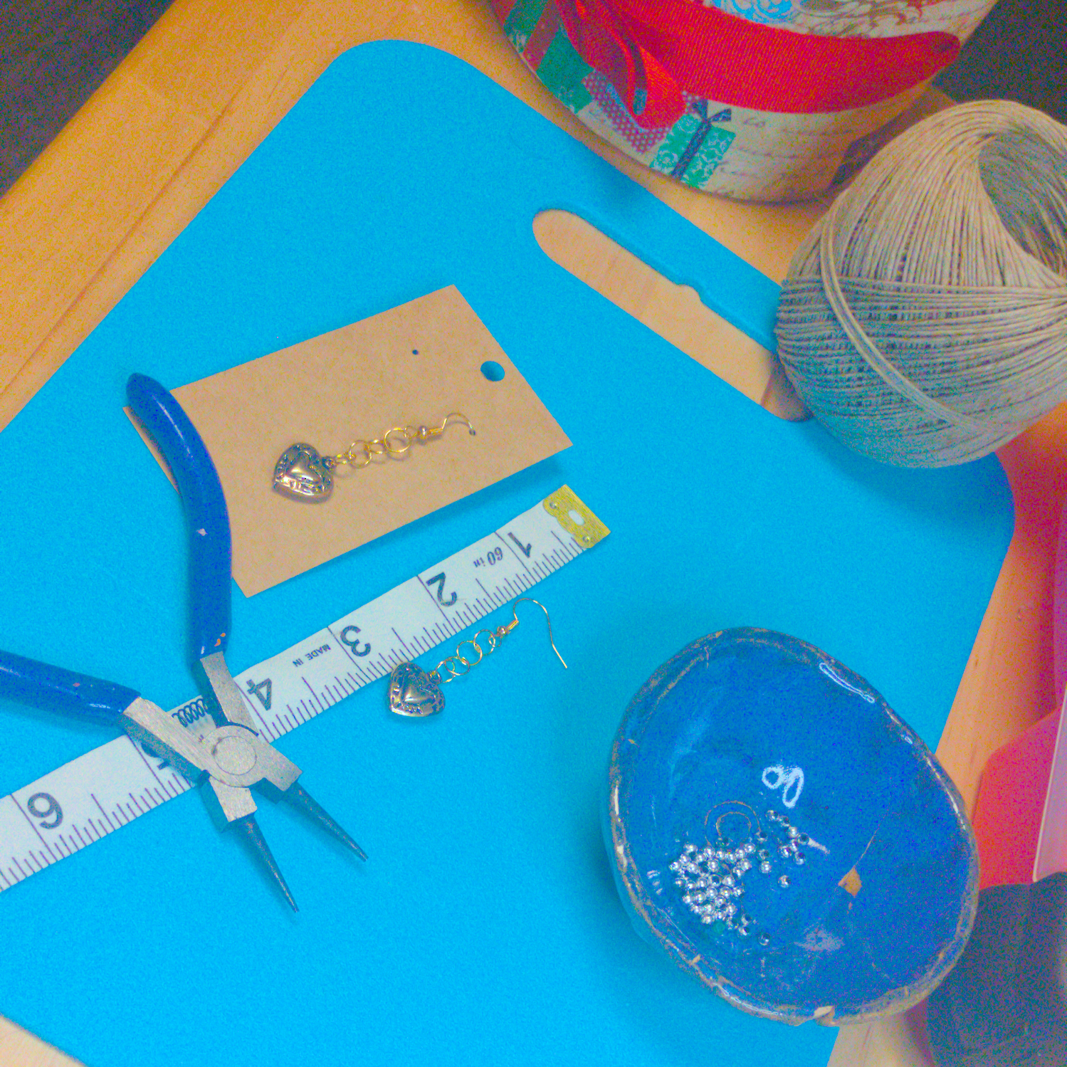 An image of a pair of golden handmade earrings being measured on a work table. The pair is 2 inches long.