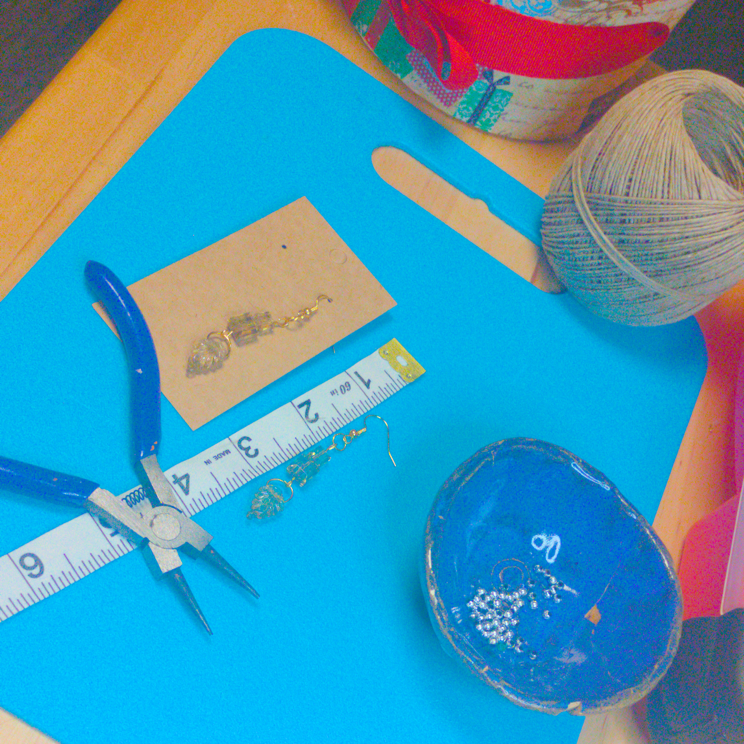 An image of a pair of clear yellow handmade earrings being measured on a work table. The pair is 2.5 inches long.
