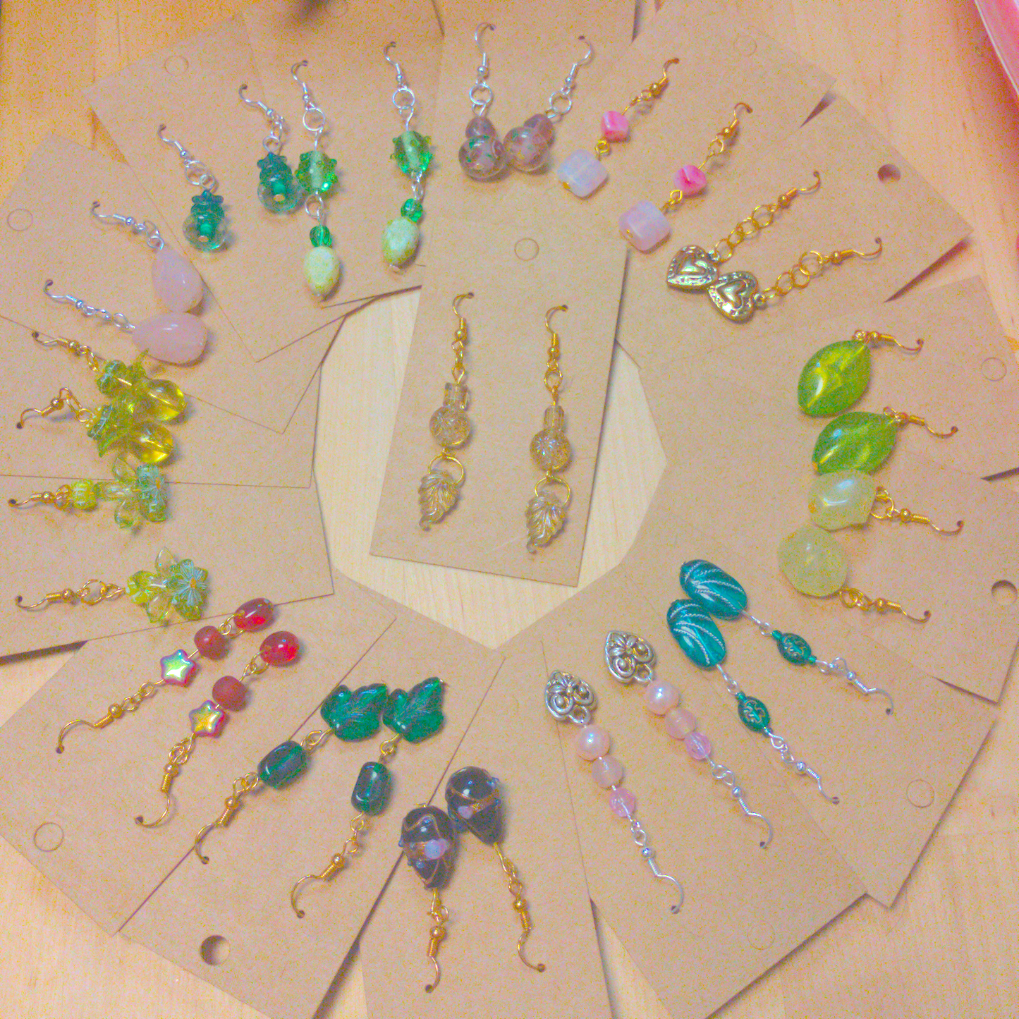 An image showing 16 different pairs of handmade earrings arranged in a circle with one pair in the middle. 