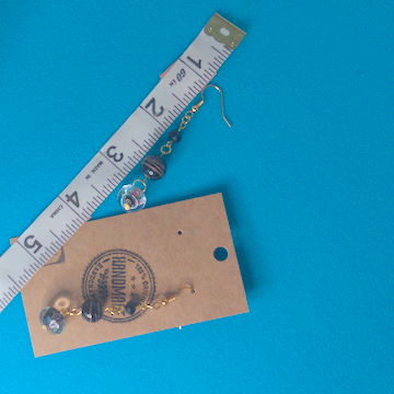 A pair of black earrings being measured on a work table. The pair is 2.5 inches long.