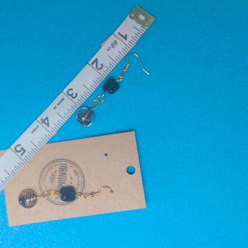 A pair of black earrings being measured on a work table. The pair is 2.25 inches long.