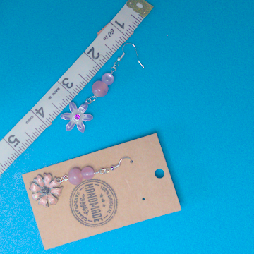A pair of pink earrings being measured on a work table. The pair is 2.75 inches long.
