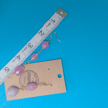 A pair of pink earrings being measured on a work table. The longer earring is 3 inches long. The shorter one is 2.5 inches long.