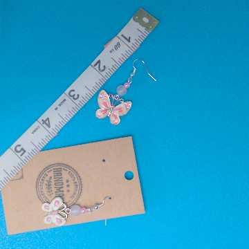 A pair of pink earrings being measured on a work table. The pair is 2 inches long.