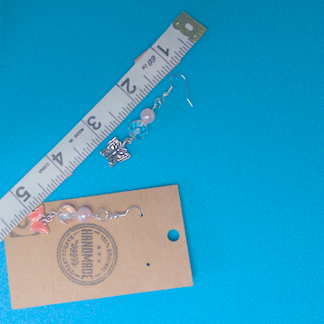 A pair of pink earrings being measured on a work table. The pair is 2.25 inches long.