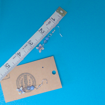 A pair of blue earrings being measured on a work table. The pair is 2 inches long.