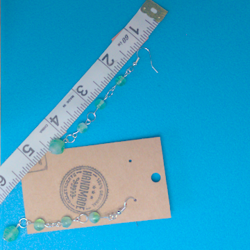 A pair of green earrings being measured on a work table. The pair is 3.5 inches long.