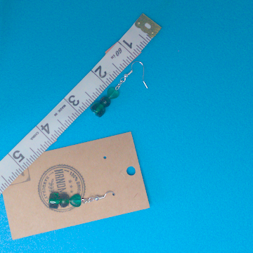 A pair of green earrings being measured on a work table. The pair is 1.75 inches long.
