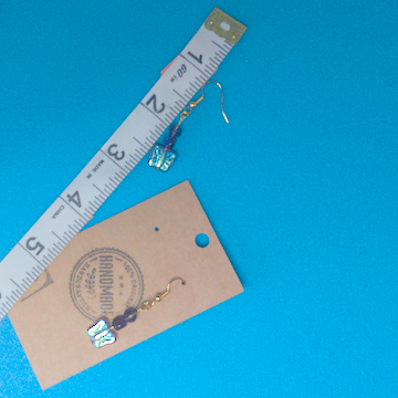 A pair of purple earrings being measured on a work table. The pair is 1.75 inches long.