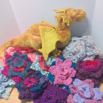 A pile of colorful crochet flowers displayed with a plus dragon.